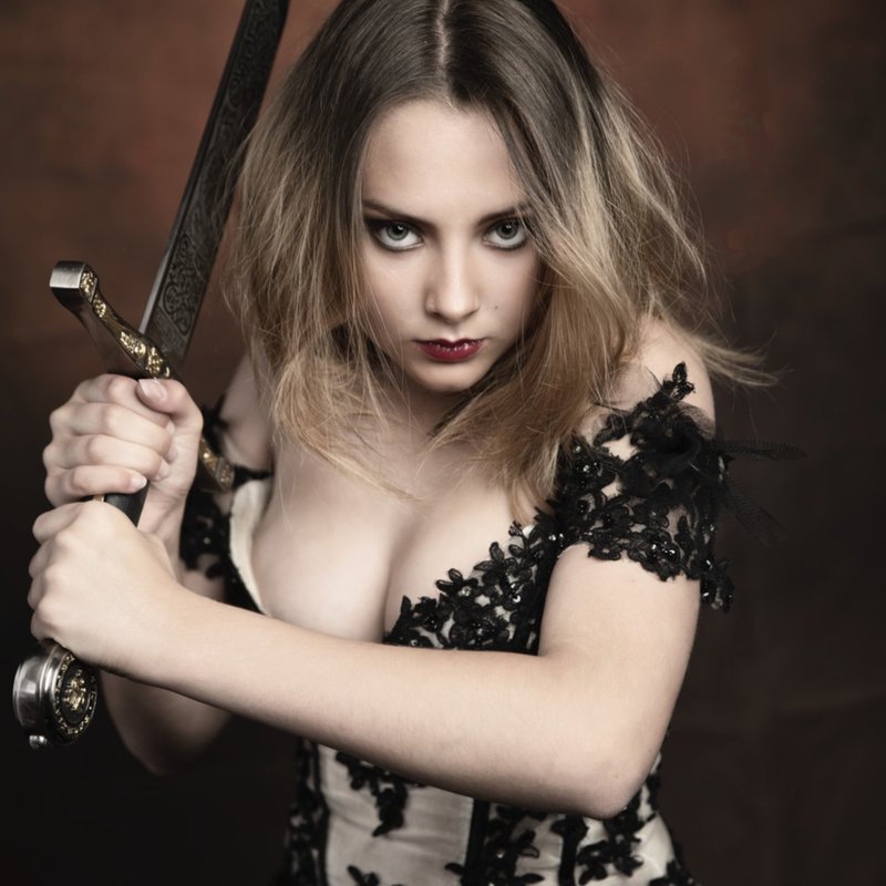 Cosplay guerrière en robe de dentelle noire, épée brandie près du visage — Fabrice Fiorucci Photographe