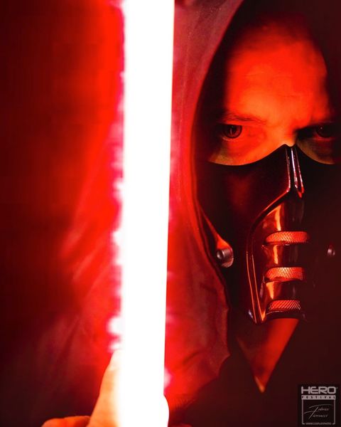 Cosplay Sith (Star Wars), capuche rouge, masque sombre et sabre laser blanc — Fabrice Fiorucci Photographe