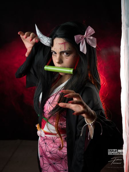 Cosplay Nezuko Kamado (Demon Slayer), kimono rose et bambou en bouche sur fond rouge — Fabrice Fiorucci Photographe