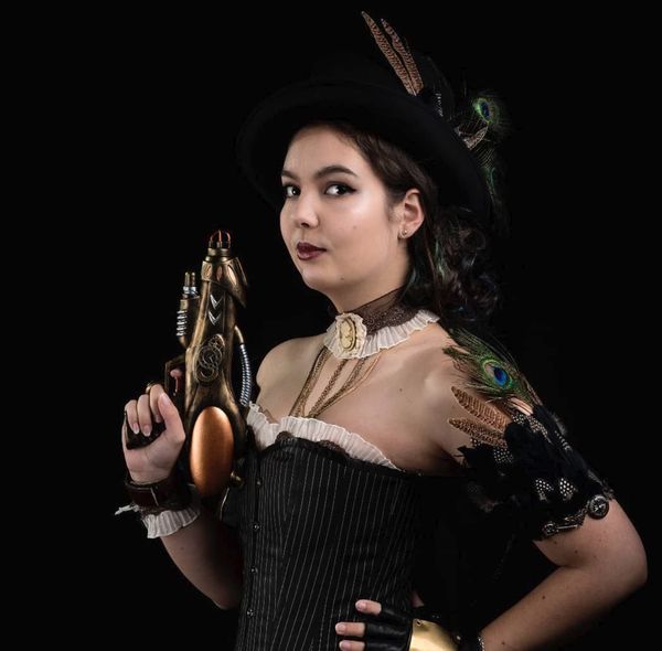 Cosplay steampunk, chapeau à plumes de paon, corset noir et pistolet doré — Fabrice Fiorucci Photographe